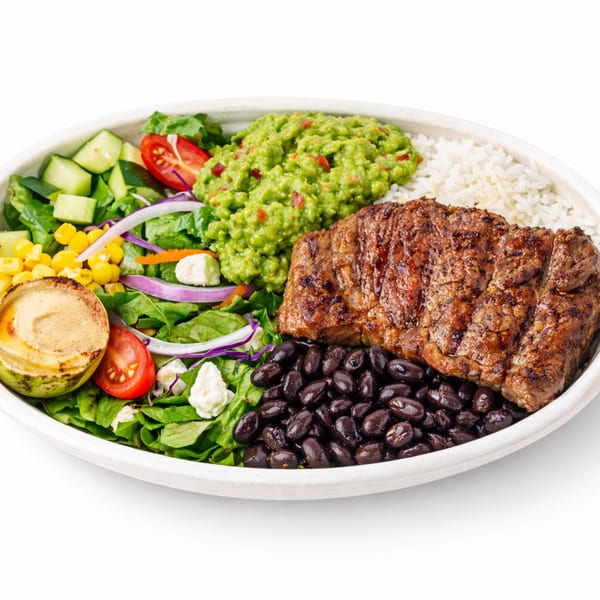 A bowl with grilled steak, black beans, white rice, guacamole, and a fresh salad.