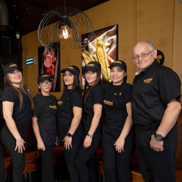 MAIKKI restaurant staff, five women and one man, in black uniforms, smiling at the camera.