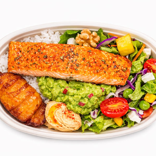 A salmon bowl with rice, guacamole, plantains, hummus, and a fresh salad with walnuts.