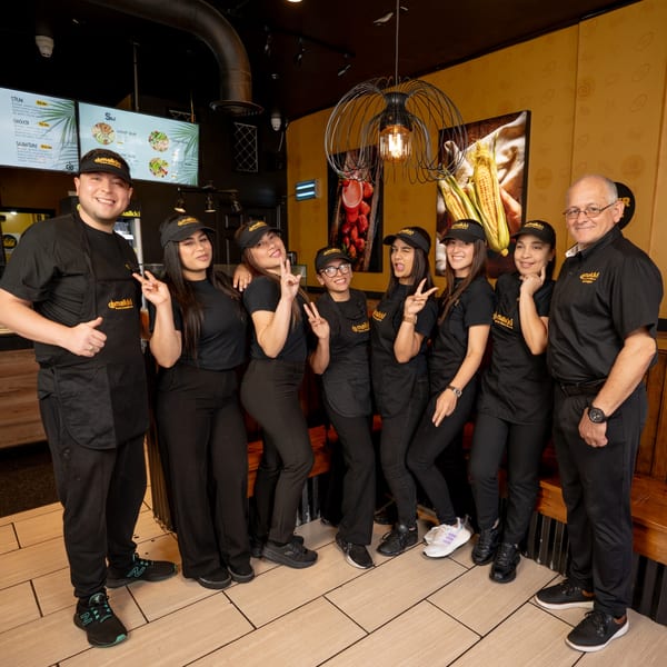 MAIKKI restaurant staff, seven women and two men, smiling and posing in their black uniforms.