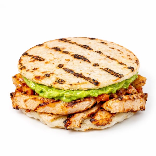 Grilled chicken and guacamole arepa on a white background.